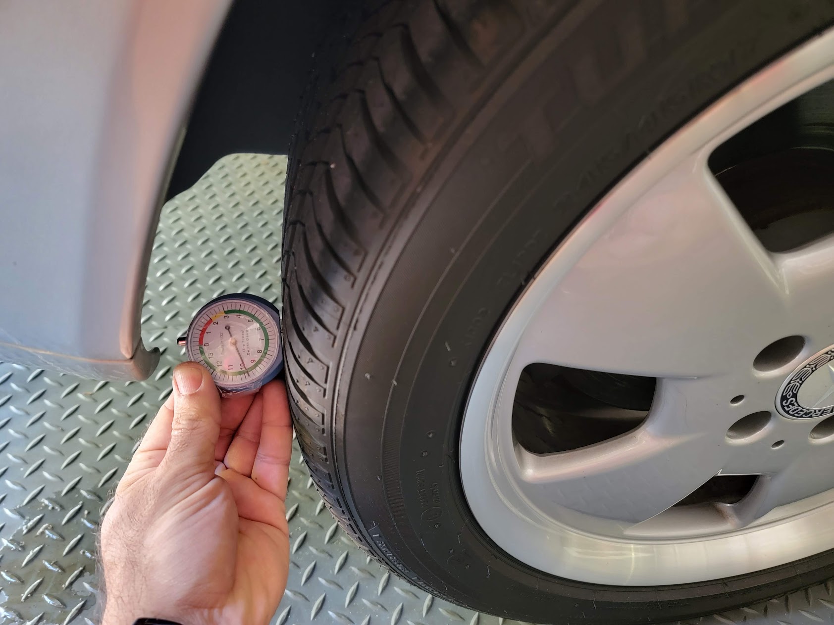 Tire tread depth gauge against a tire