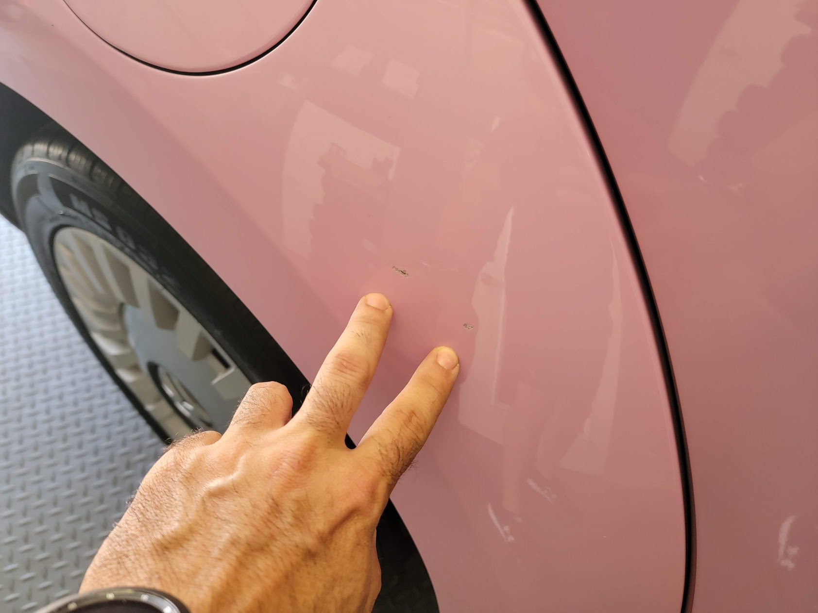Inspector pointing at paint chips on pink body panel
