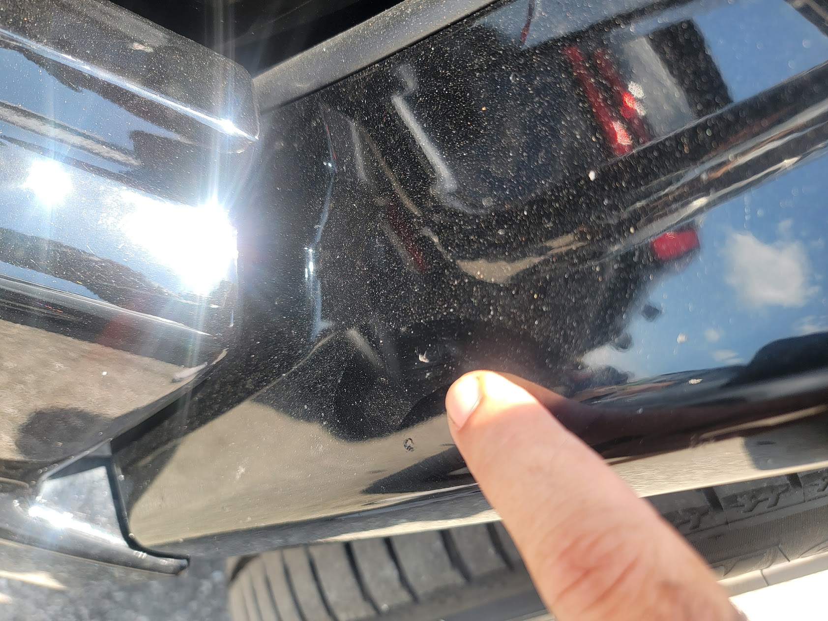 Inspector pointing at paint defect on black bumper